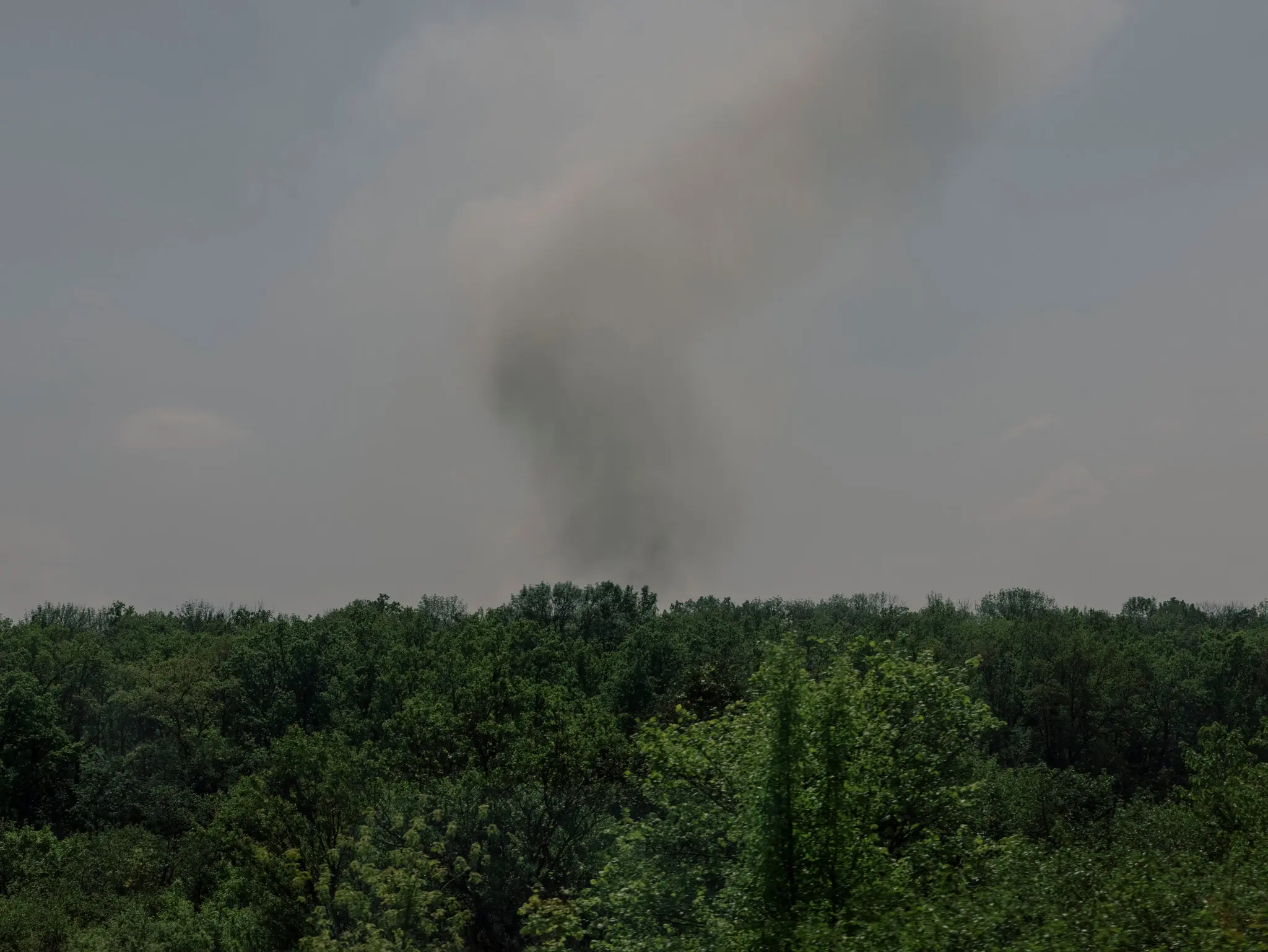 Дим піднімається в небо з боку села на українському кордоні.